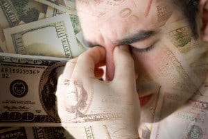 guy pinching bridge of nose with money in background