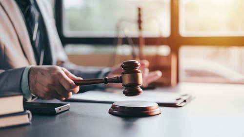 An adult lawyer holds a gavel symbolising law and justice decision in the courtroom office. This image represents fairness and legal matters for court.